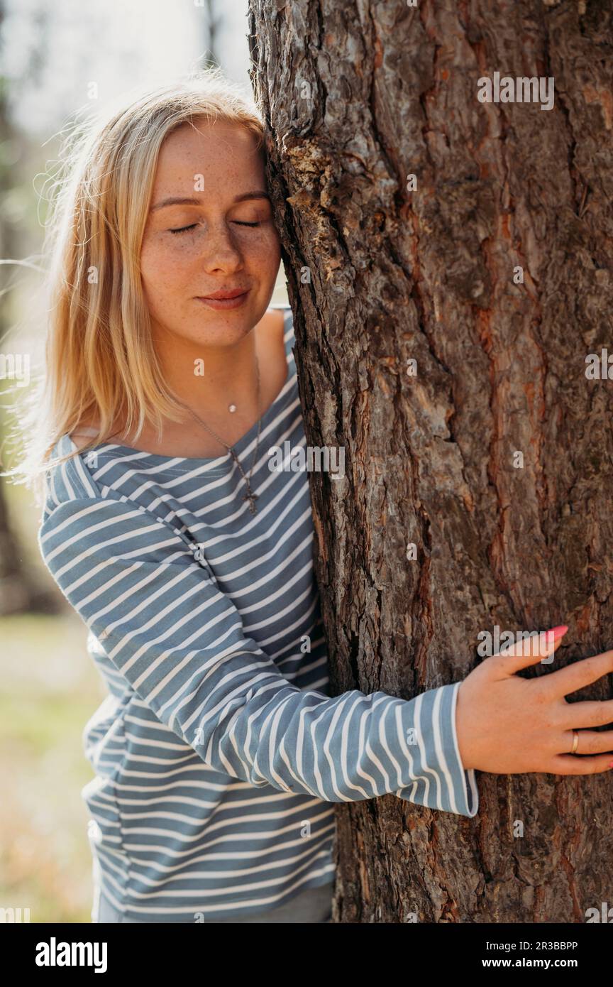 Young woman with eyes closed hugging tree in forest Stock Photo - Alamy