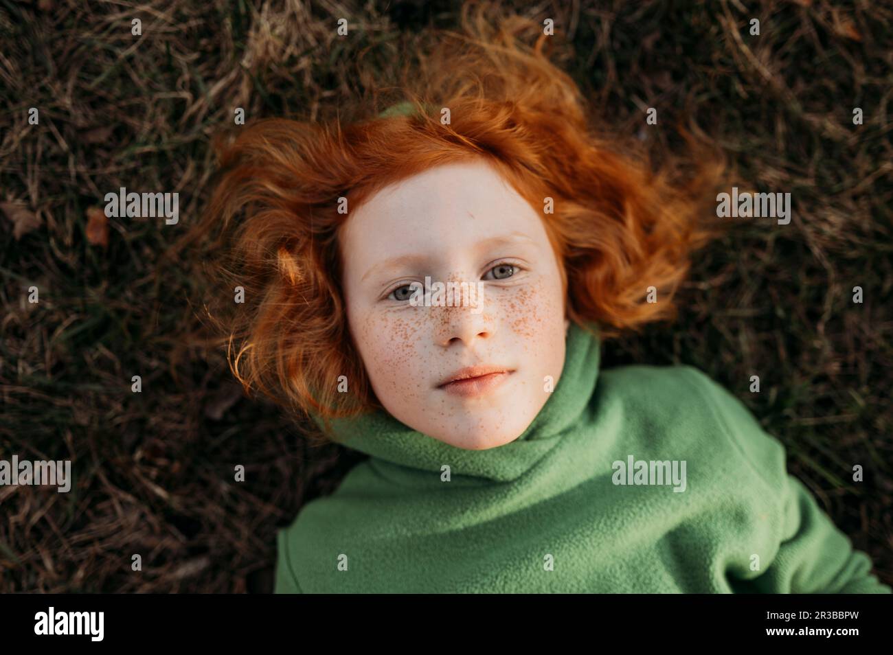 Redhead girl with freckles lying in field Stock Photo
