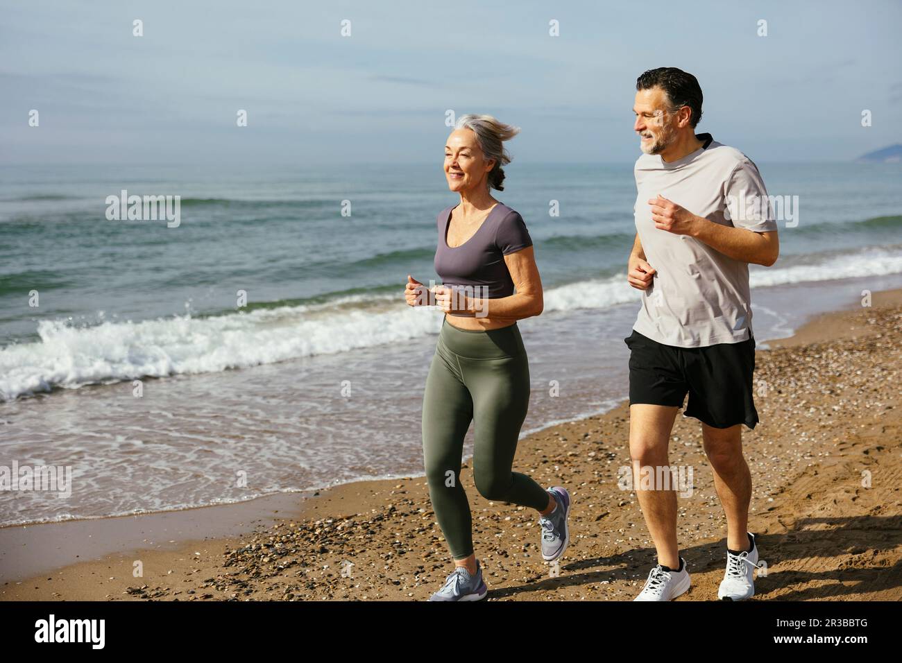 Mature couple jogging together at sunny day Stock Photo