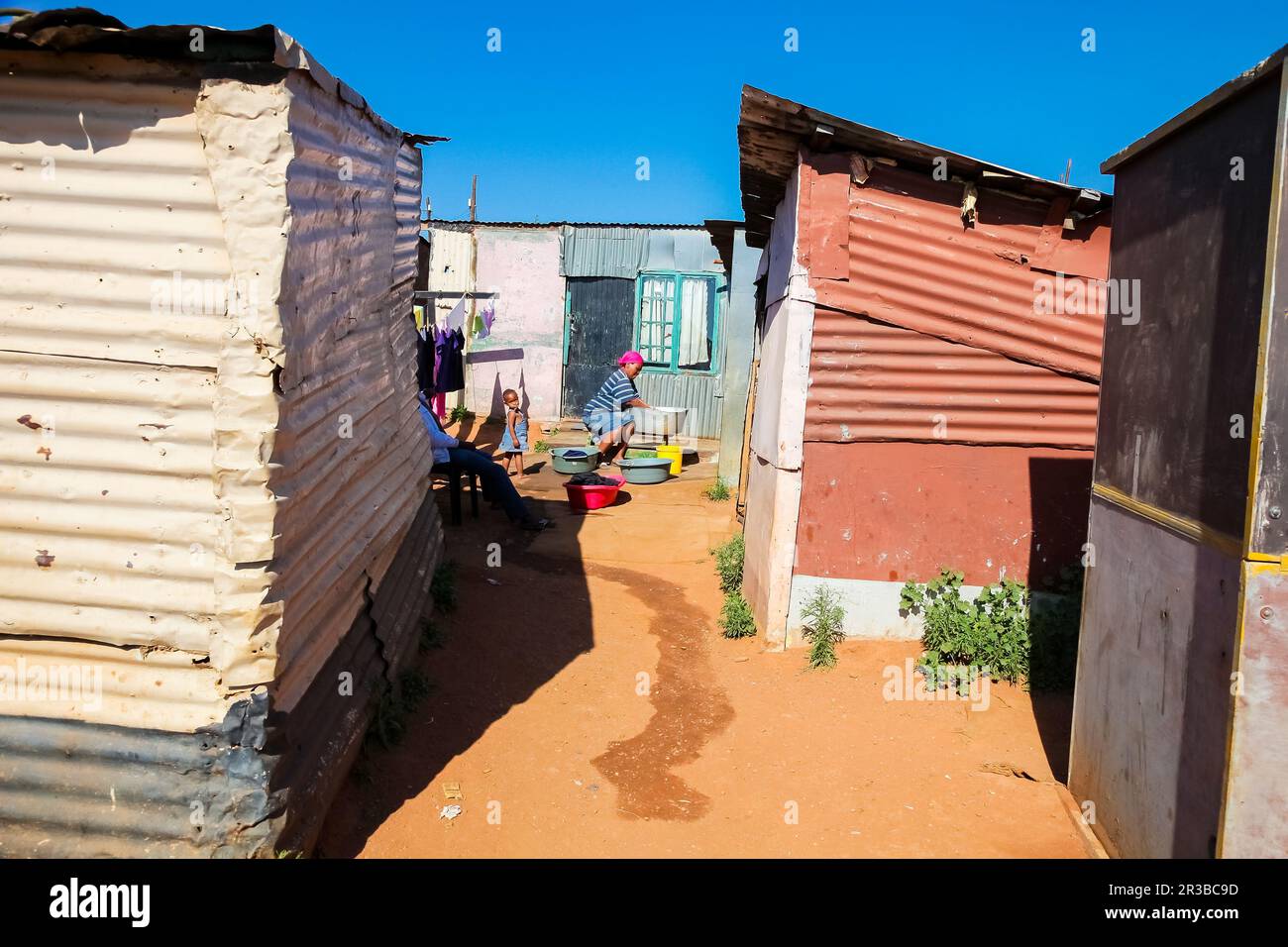 African mother and child washing clothes in Low-income Soweto neighborhood Stock Photo