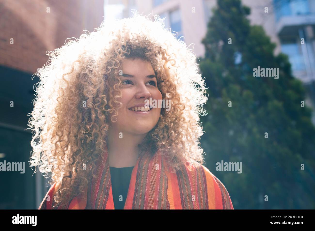 Thoughtful young woman with curly hair Stock Photo - Alamy