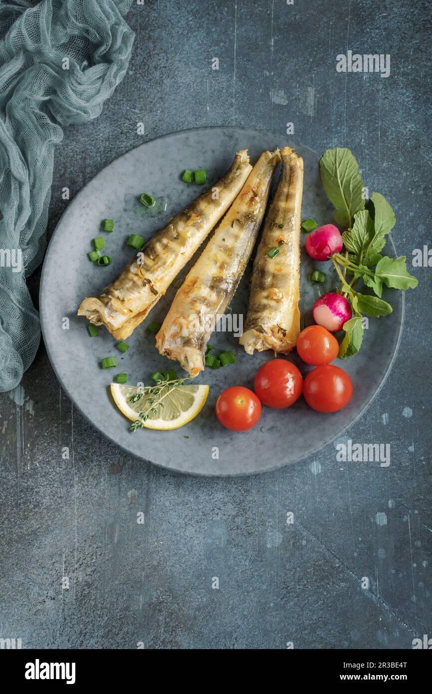 Baked mackerel icefish with tomato, radish and lemon Stock Photo Alamy