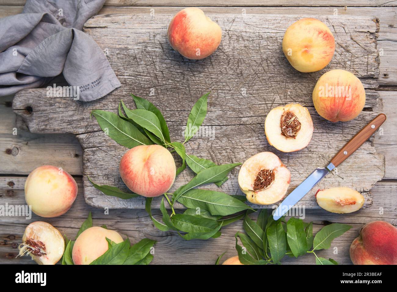 Several ripe juicy peaches on a wooden surface. Peach fruits on the wooden board. Green living conce Stock Photo