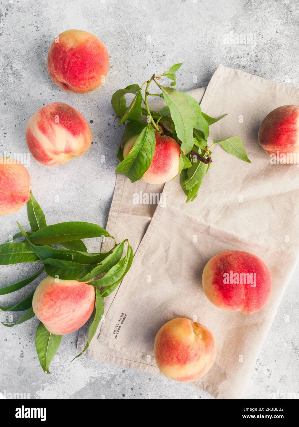 Several ripe juicy peaches on a gray background. Peach fruits on the wooden board. Green living conc Stock Photo