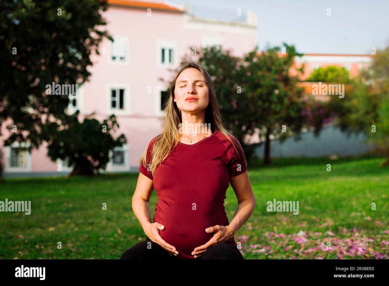 Pregnant woman meditating with hands on stomach on lawn Stock Photo - Alamy
