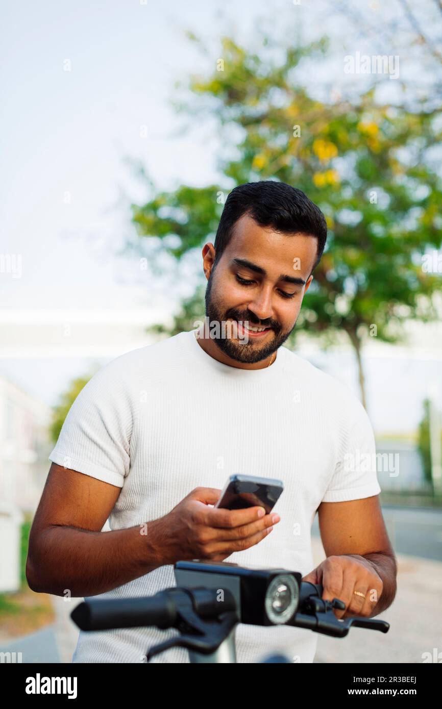 Man using smart phone on electric scooter Stock Photo