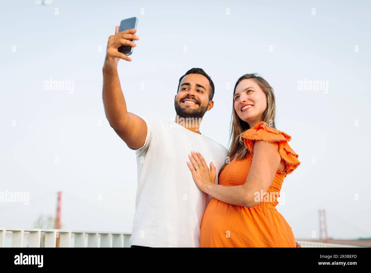Smiling man taking selfie with pregnant woman Stock Photo
