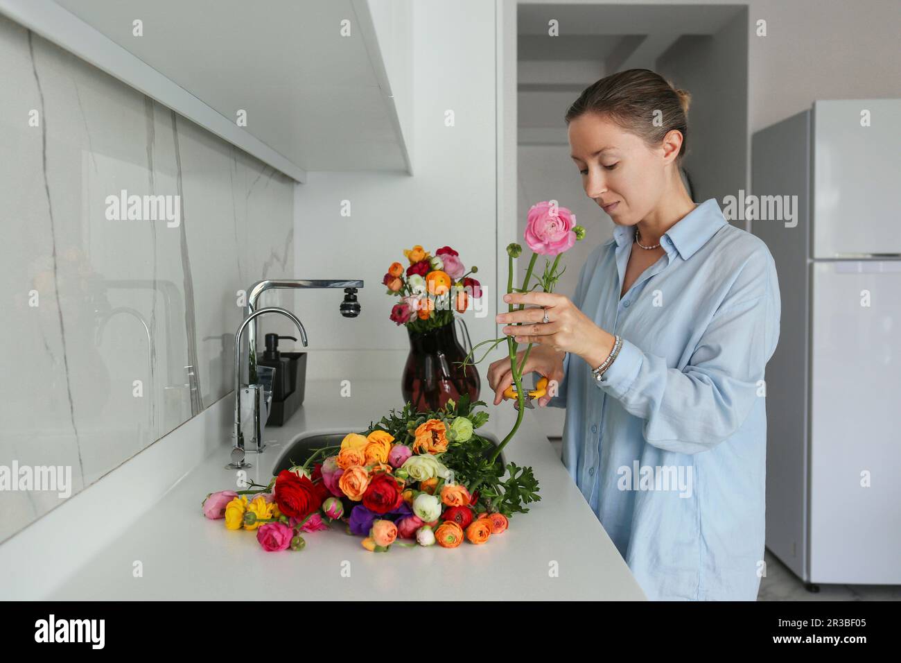 Woman pruning flowers in kitchen at home Stock Photo