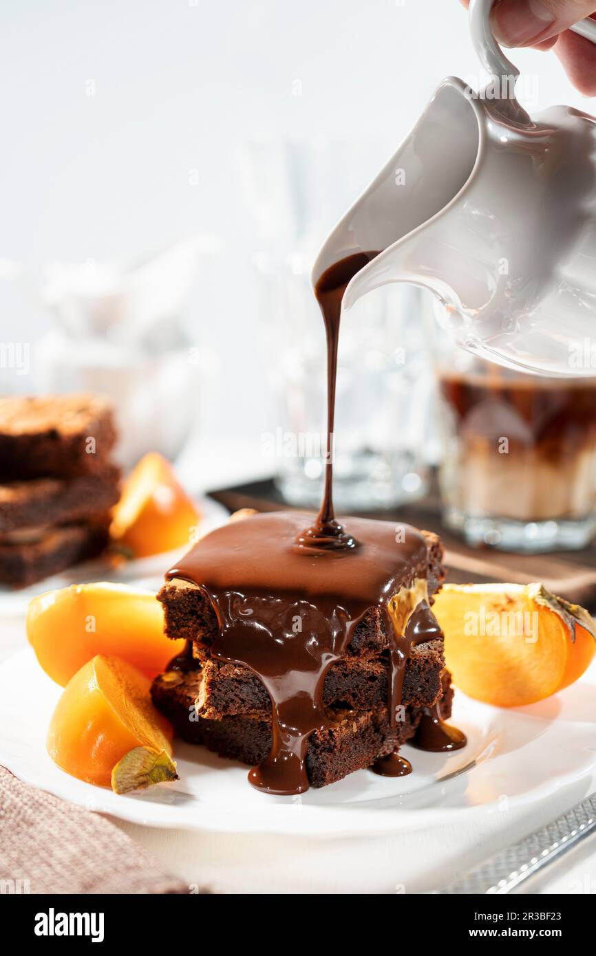 Chocolate sauce being poured over gluten-free brownies Stock Photo