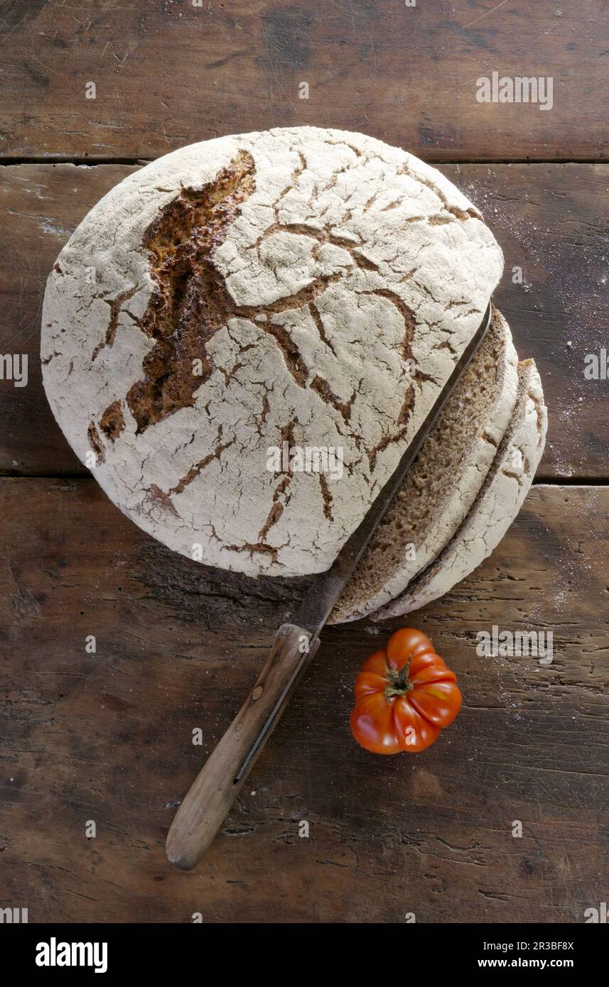 A loaf of fresh country bread, sliced on a wooden surface Stock Photo