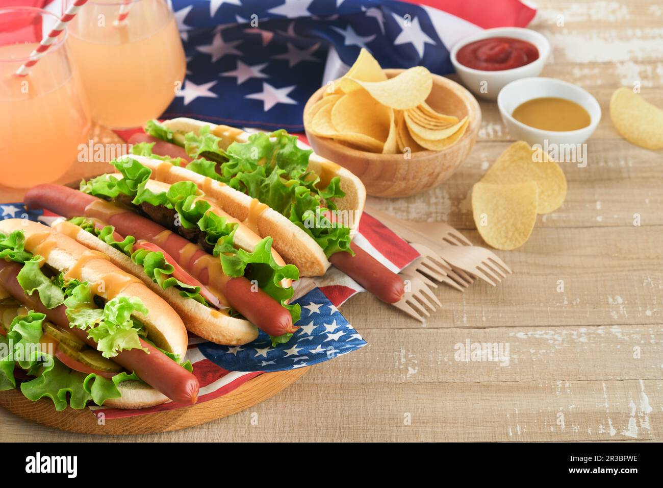 4th of July American Independence Day traditional picnic food. Hot dog with potato chips and cocktail, American flags and symbols of  USA Patriotic pi Stock Photo