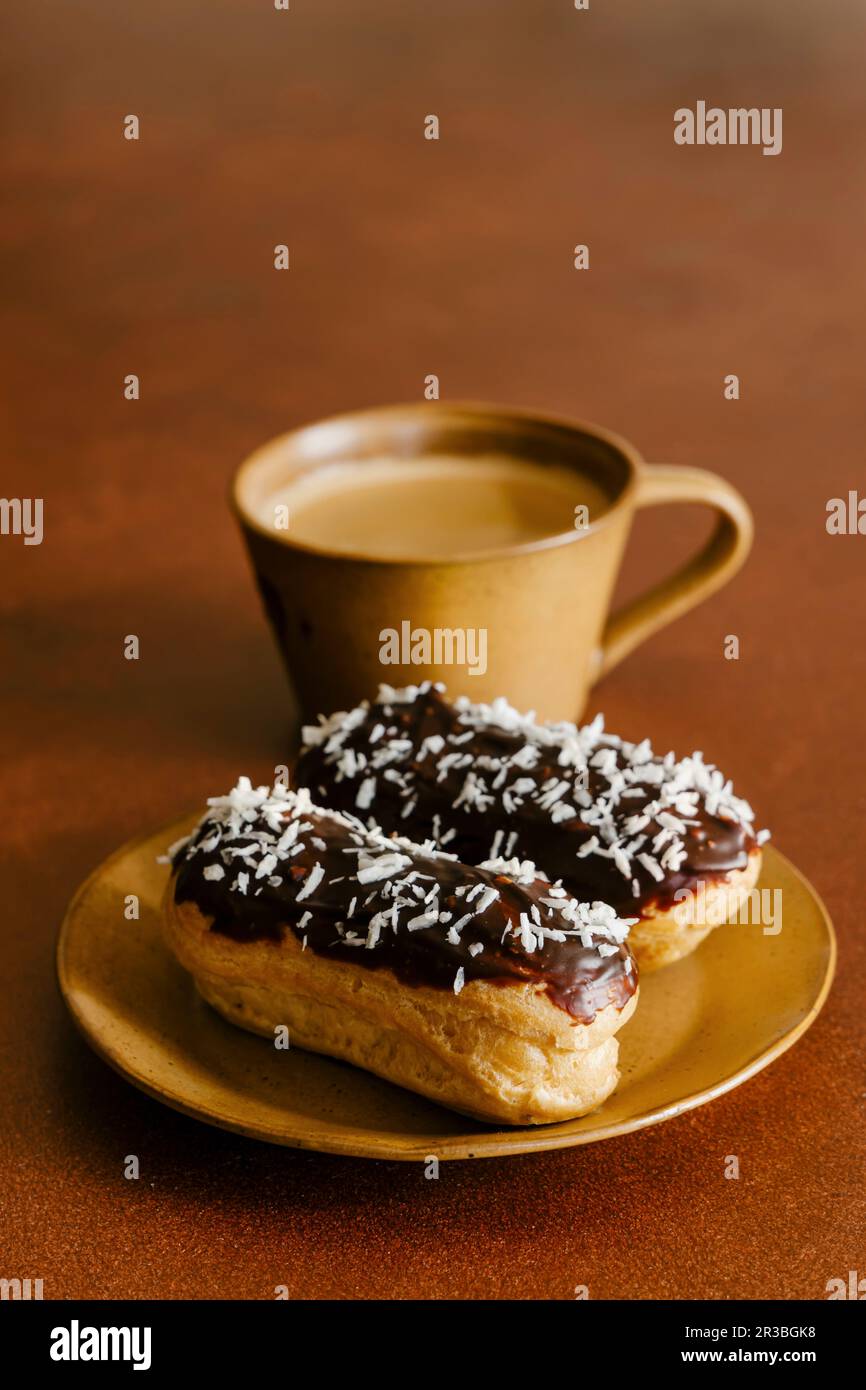 Coconut eclairs and cup of coffee Stock Photo