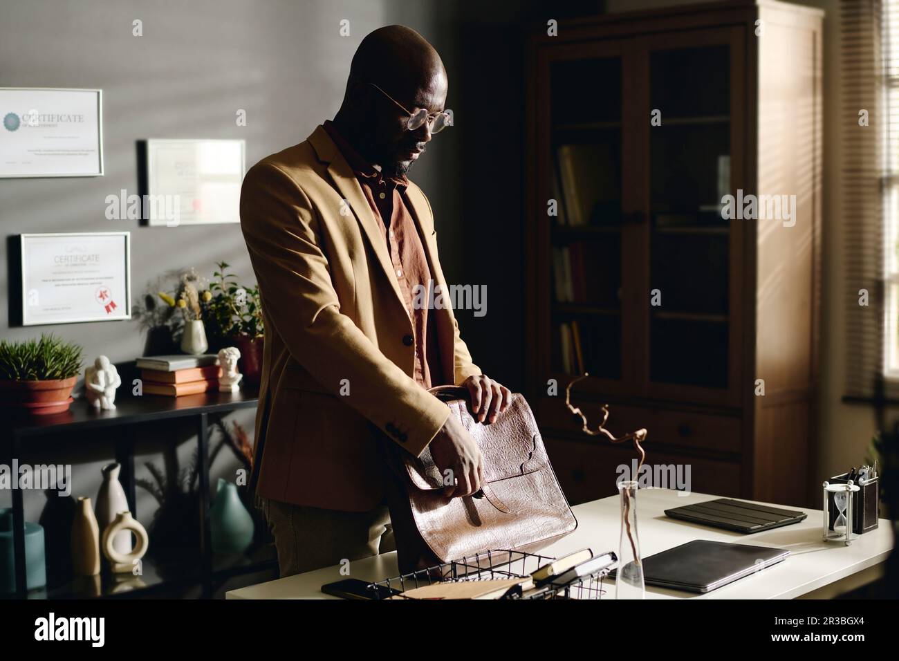 Psychologist opening briefcase standing by desk in office Stock Photo