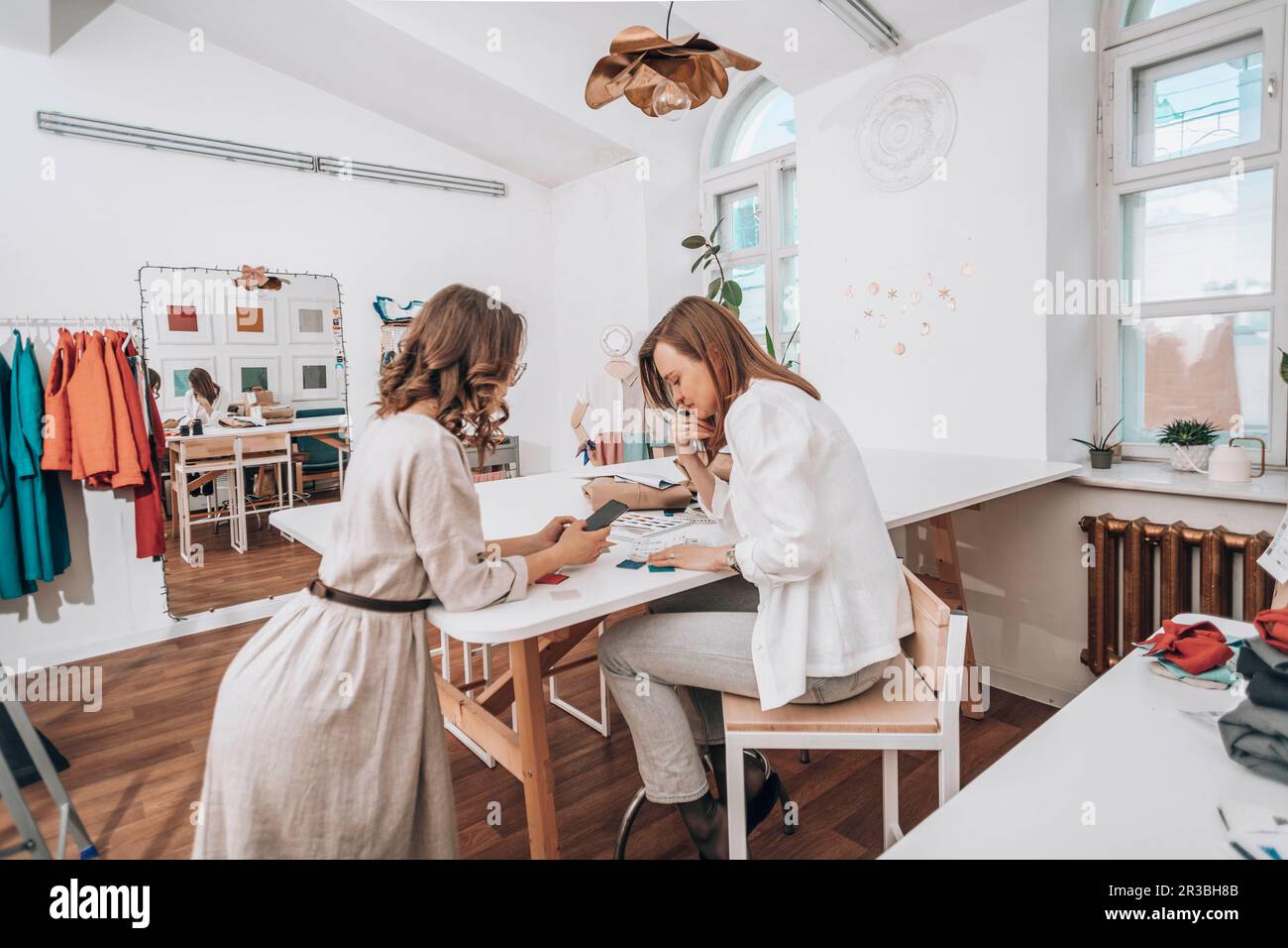 Fashion designers discussing over smart phone at workshop Stock Photo