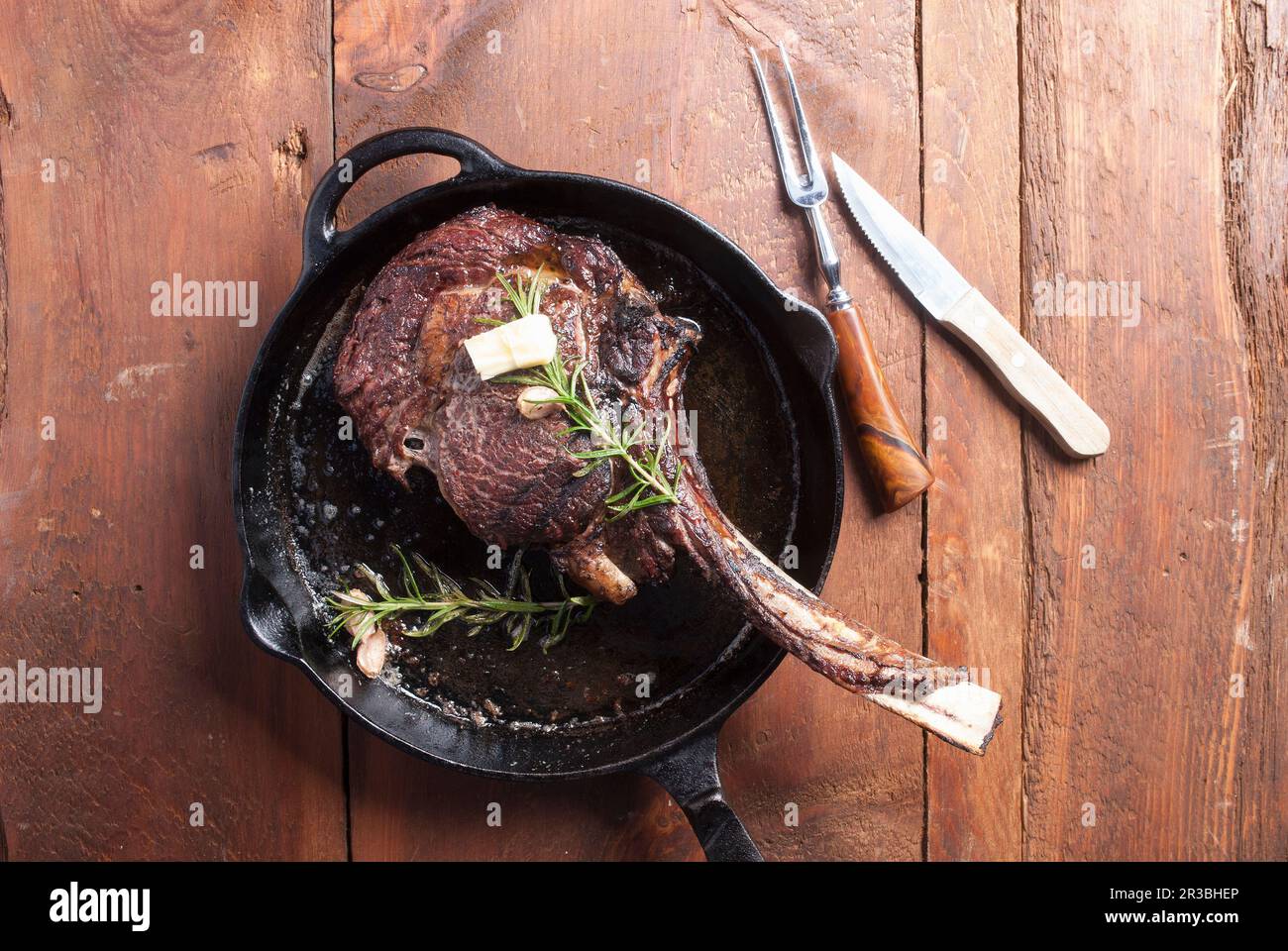 Tomahawk steak in cast iron pan, seasoned with butter and rosemary
