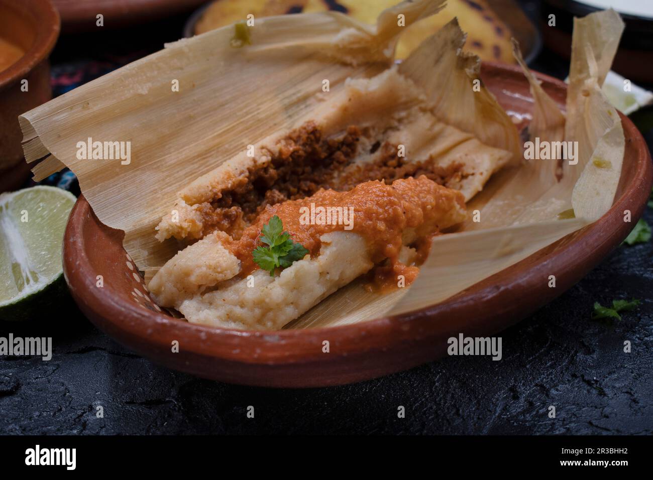 Vegan tamales filled with seitan, masa, chile verde and served with ranchero sauce, cream and chili beans Stock Photo