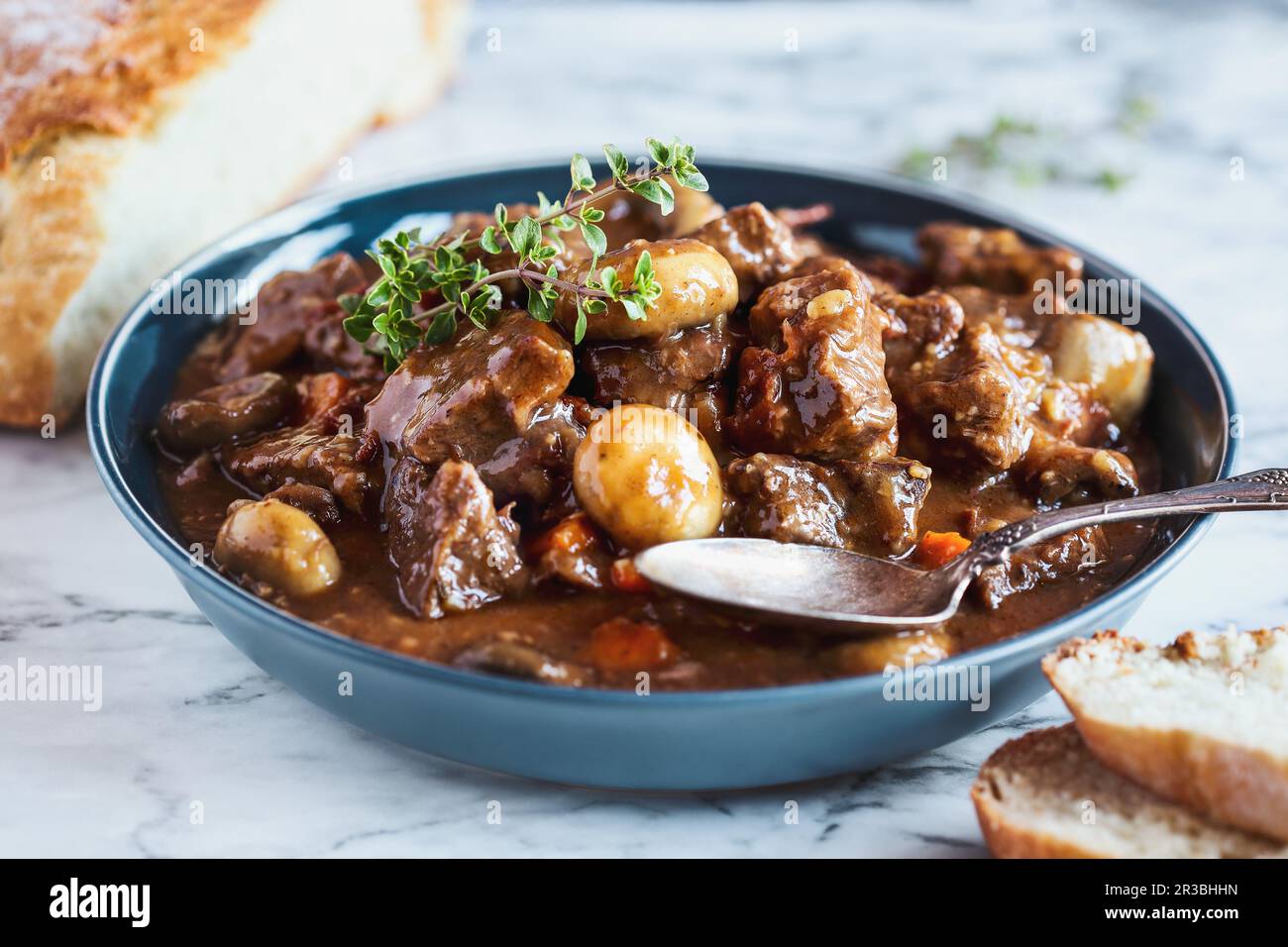 Beef Bourguignon garnished with fresh lemon thyme and served with homemade artisan bread Stock Photo