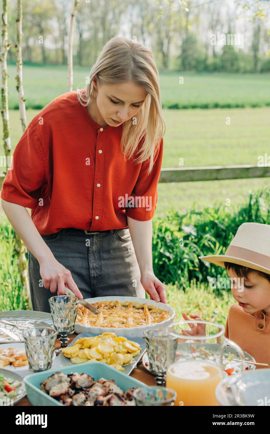 Mother cutting pie at dining table in back yard Stock Photo