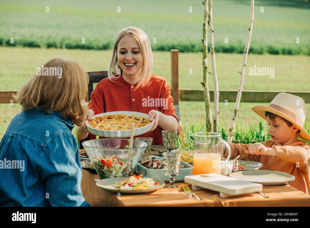 Happy family having healthy lunch at dining table in back yard Stock Photo