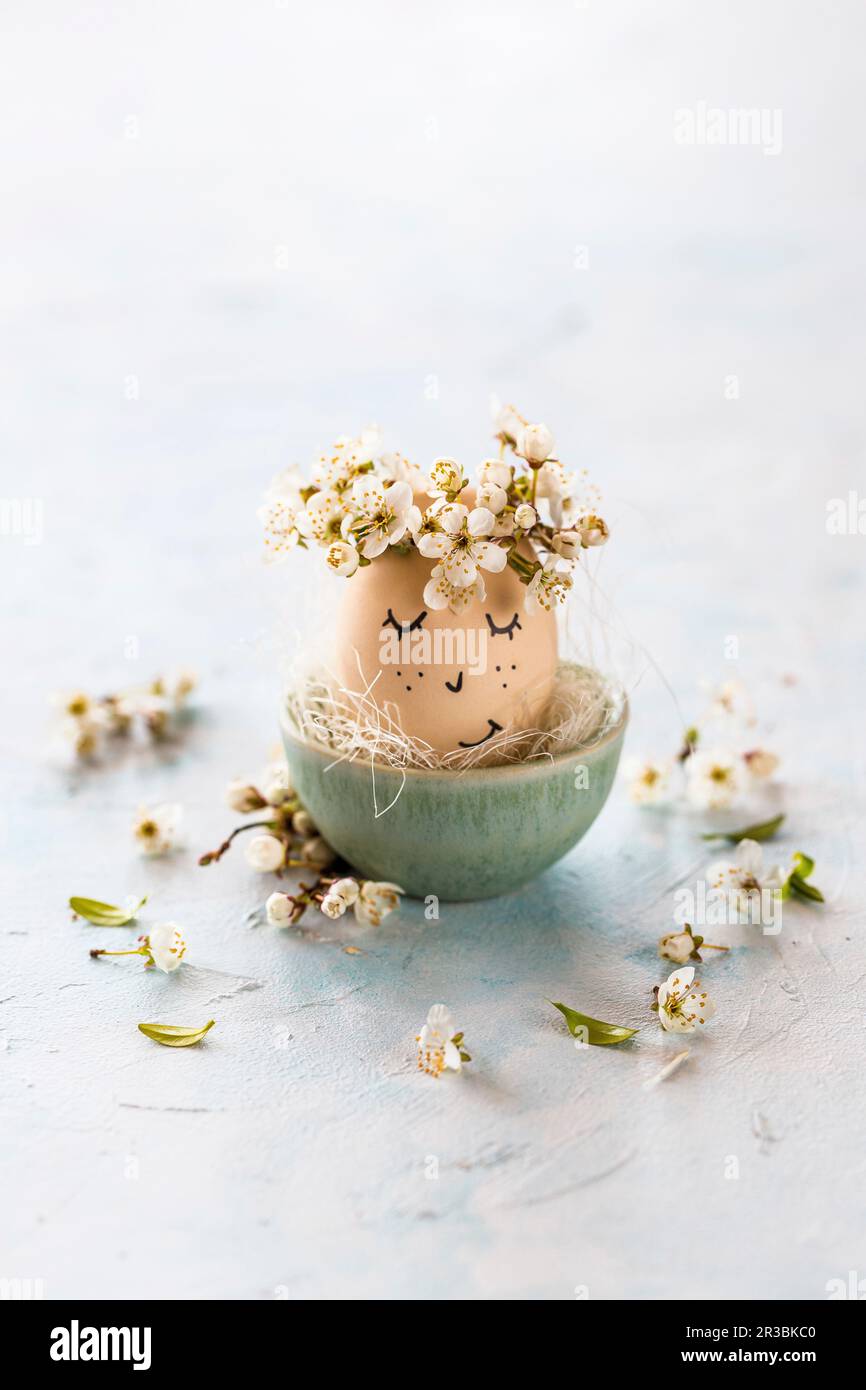 An Easter egg with a face and flower petals Stock Photo