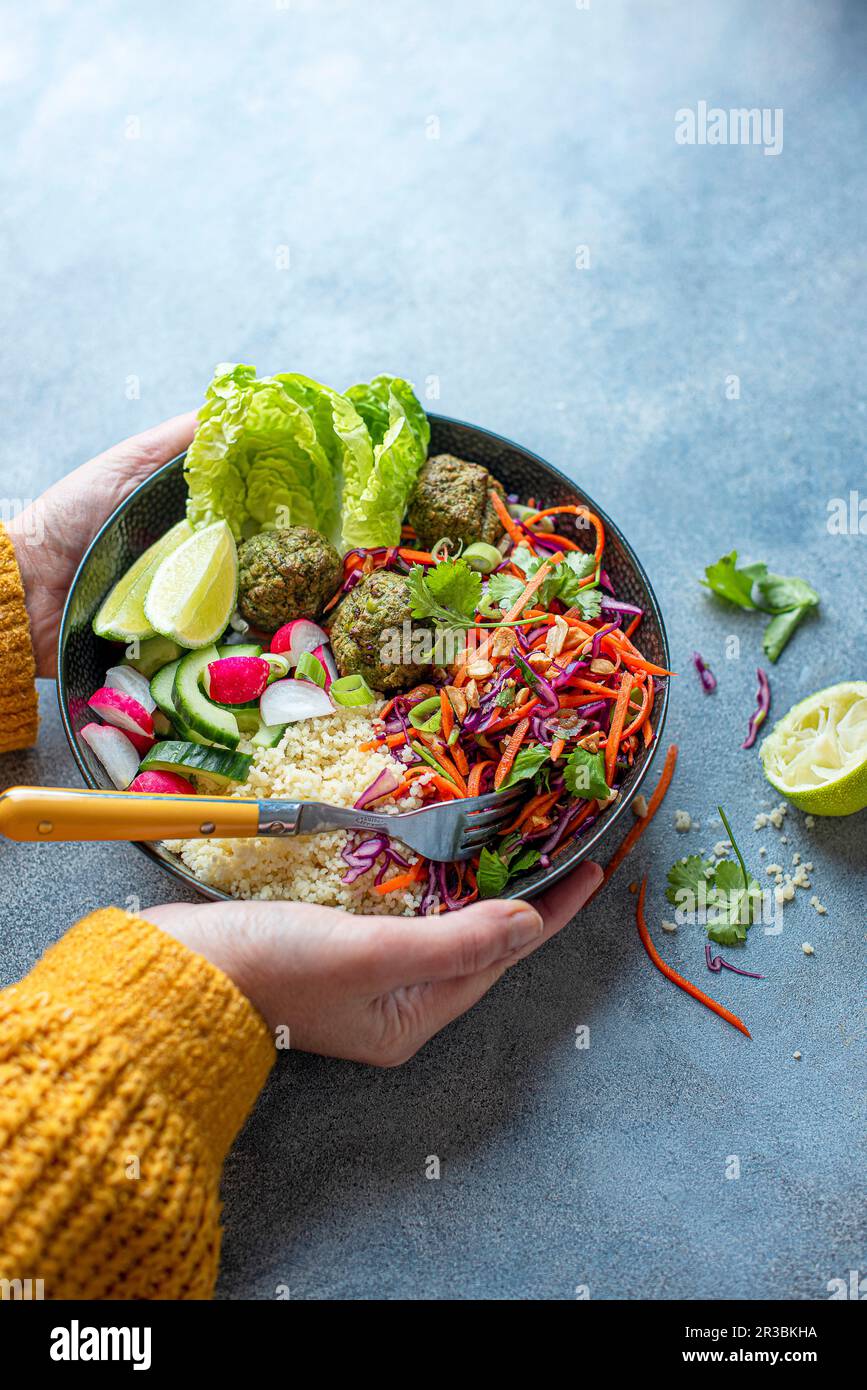 Vegeterian Buddha bowl with lime and penut slaw, spinach falafels, couscous and salad Stock Photo
