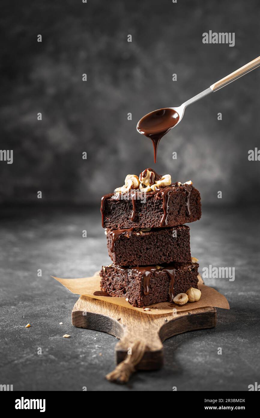 Stack of brownie with nuts and pouring chocolate sauce Stock Photo