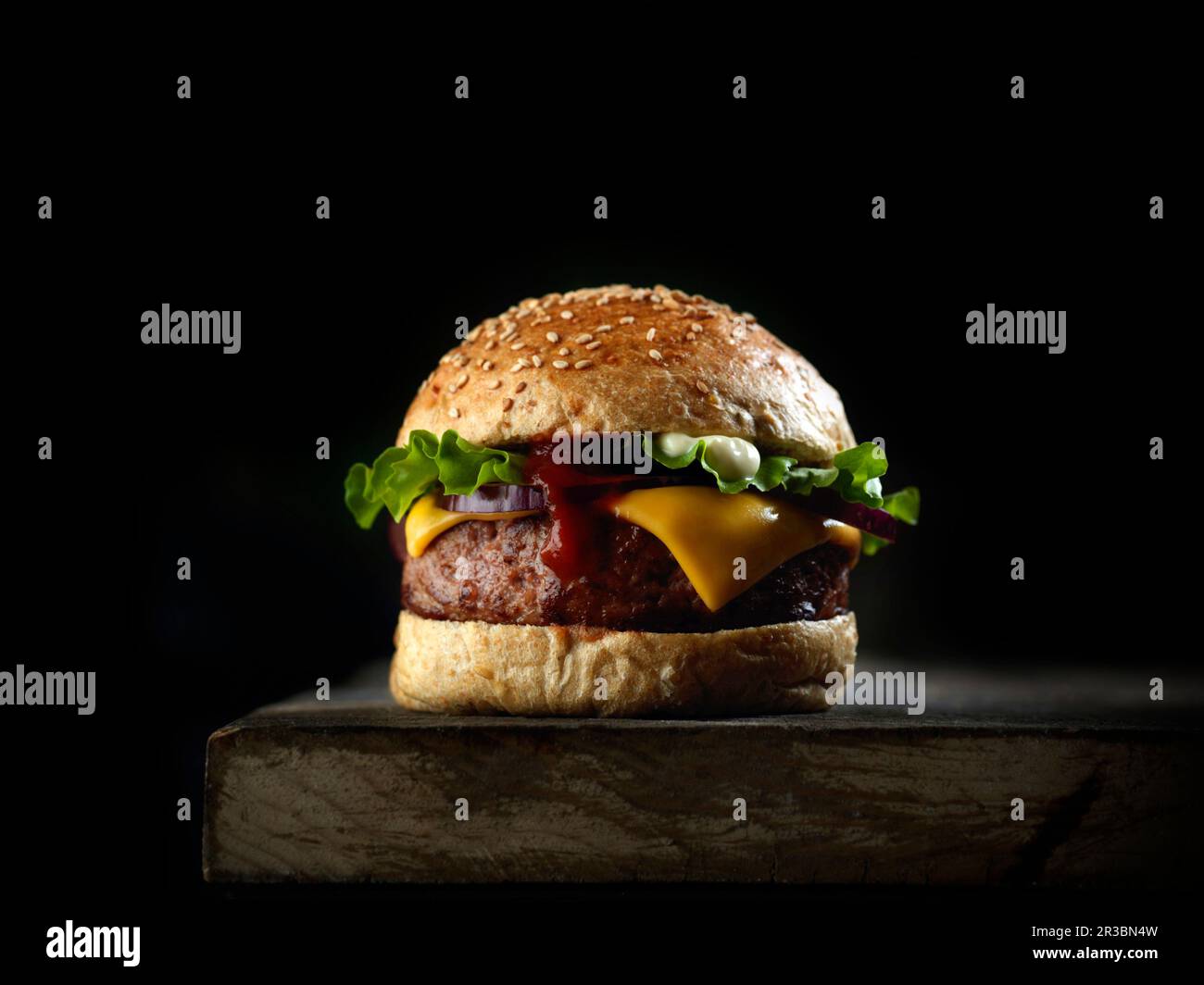 Burger with cheese and lettuce against a black background Stock Photo