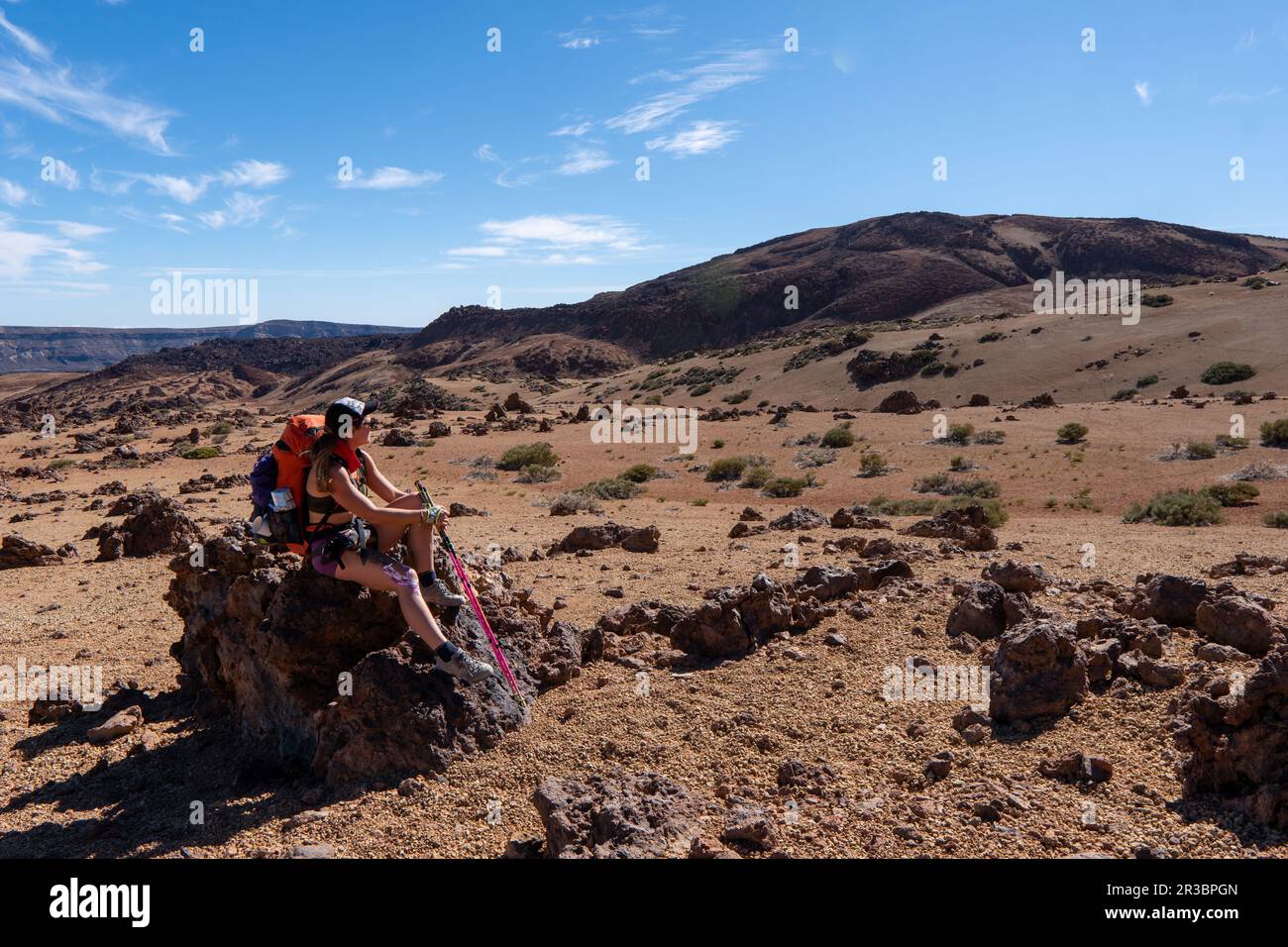 Young woman hiker with backpack trekking near Pico del Teide mountain in El Teide National park. Tenerife, Canary Islands, Spain Stock Photo