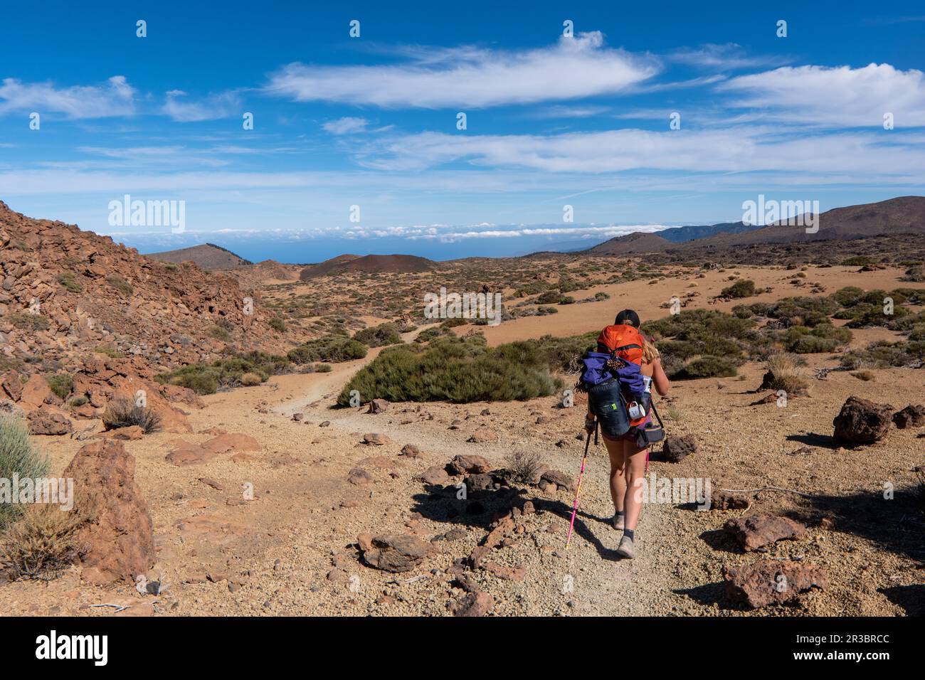 Young woman hiker with backpack trekking near Pico del Teide mountain in El Teide National park. Tenerife, Canary Islands, Spain Stock Photo