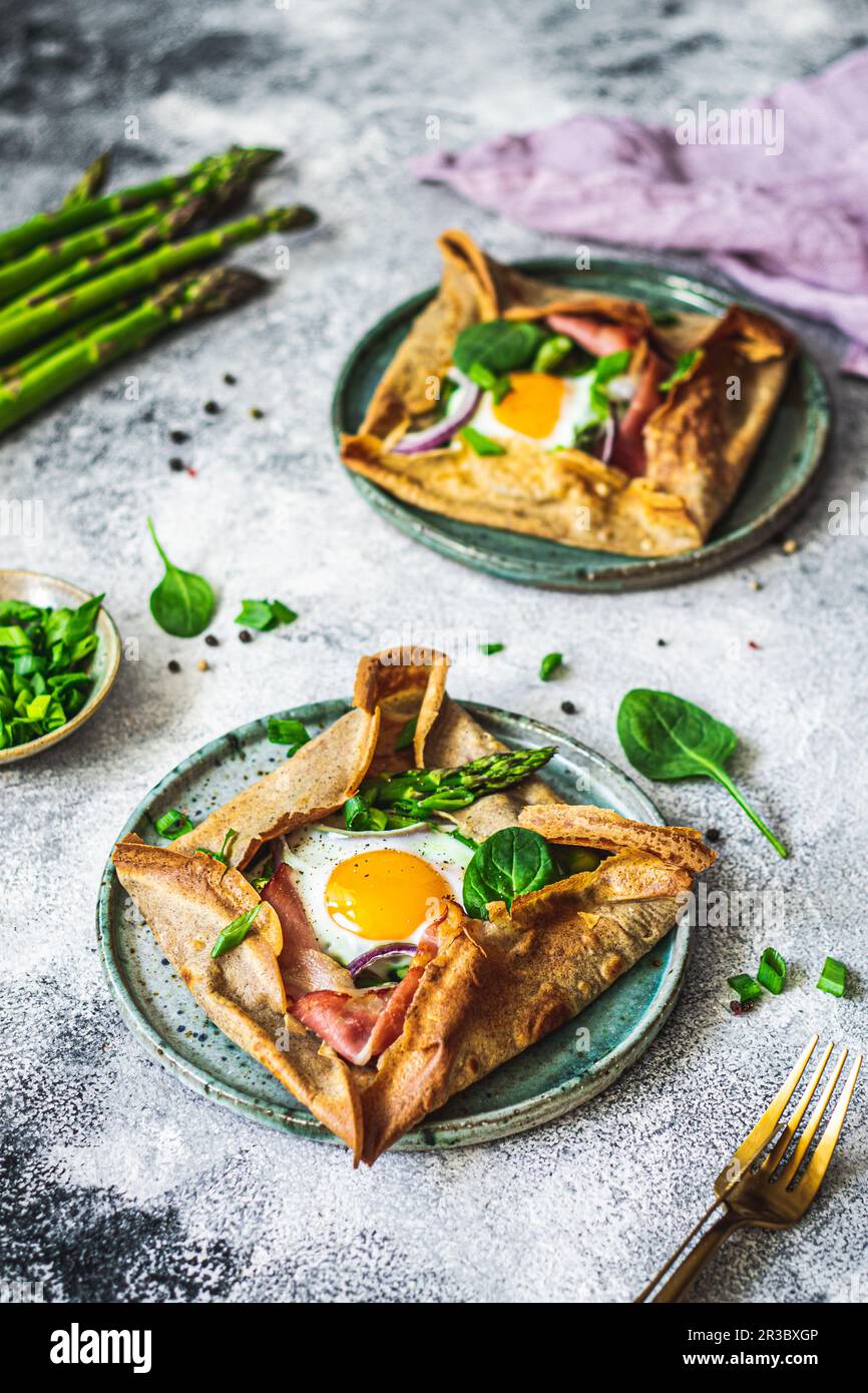 Baked pancakes with asparagus, Parma ham, spinach and egg Stock Photo