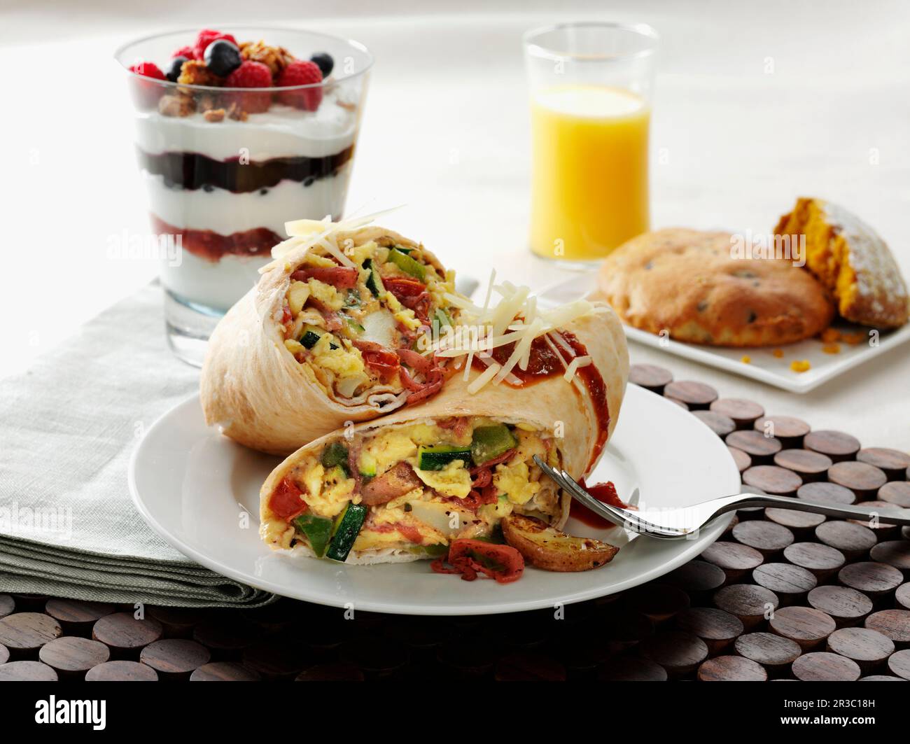 Egg and vegetable breakfast wrap sandwich with yogurt and fruit parfait with orange juice Stock Photo