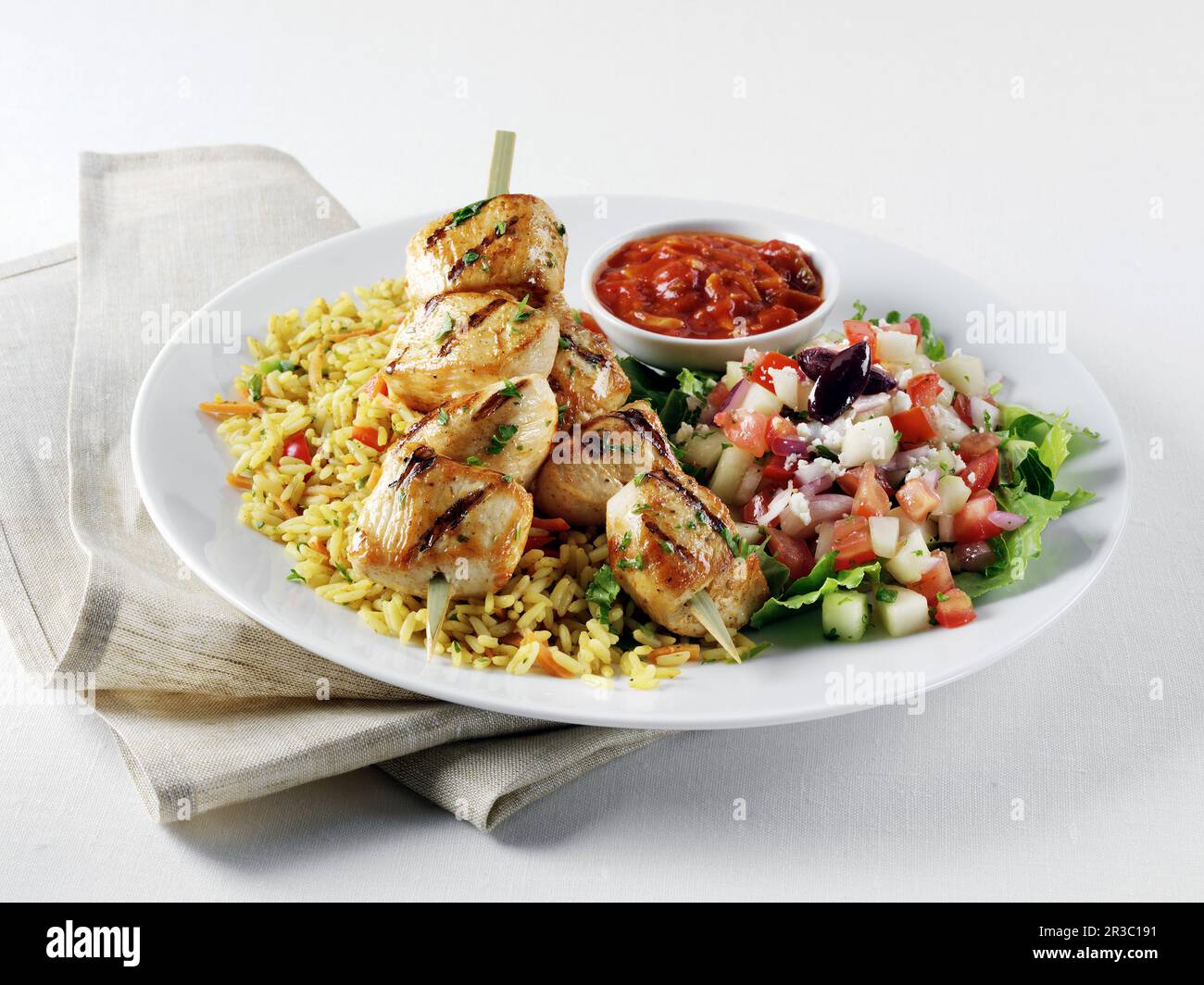 Chicken kabobs on Mediterranean yellow rice, Greek salad and Harrisa