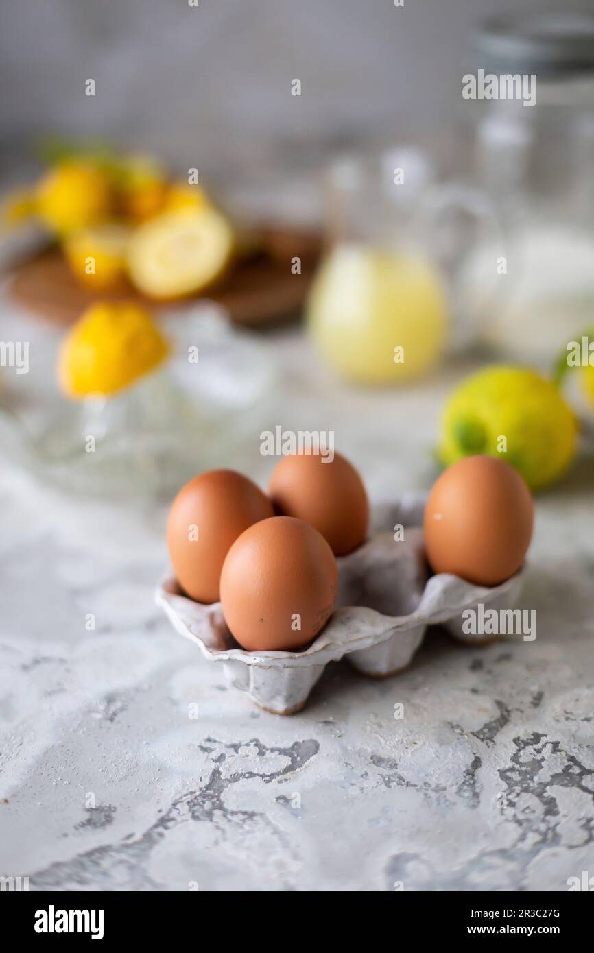 Fresh eggs in an egg carton, lemons, a lemon squeezer and lemon juice