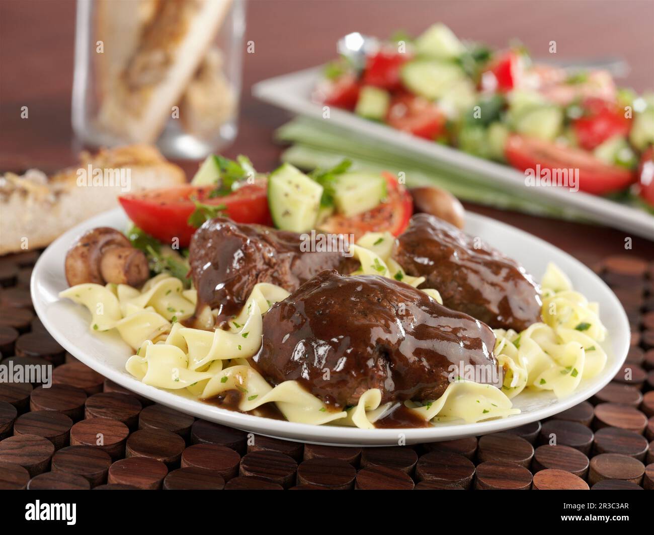 Braised beef short ribs with braising liquid on a bed of pasta with