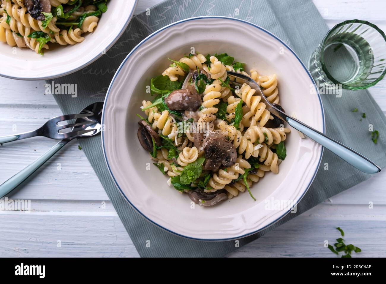 Vegan pasta and mushroom pan with rocket, pine nuts and almond cheese Stock Photo