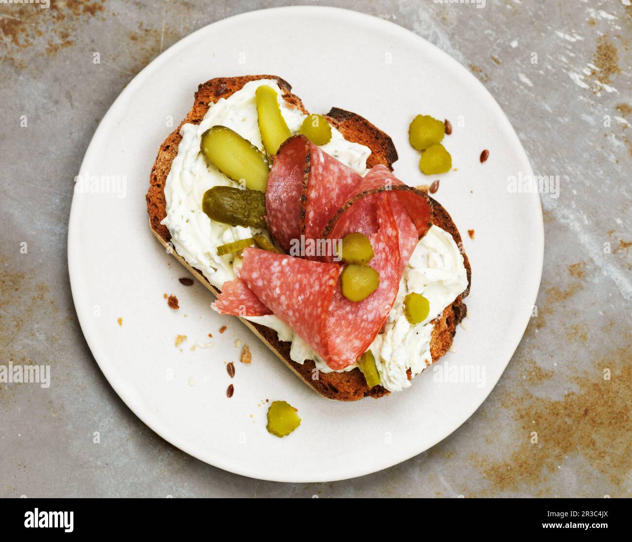 Open faced sandwich with cream cheese, salami, and pickles Stock Photo