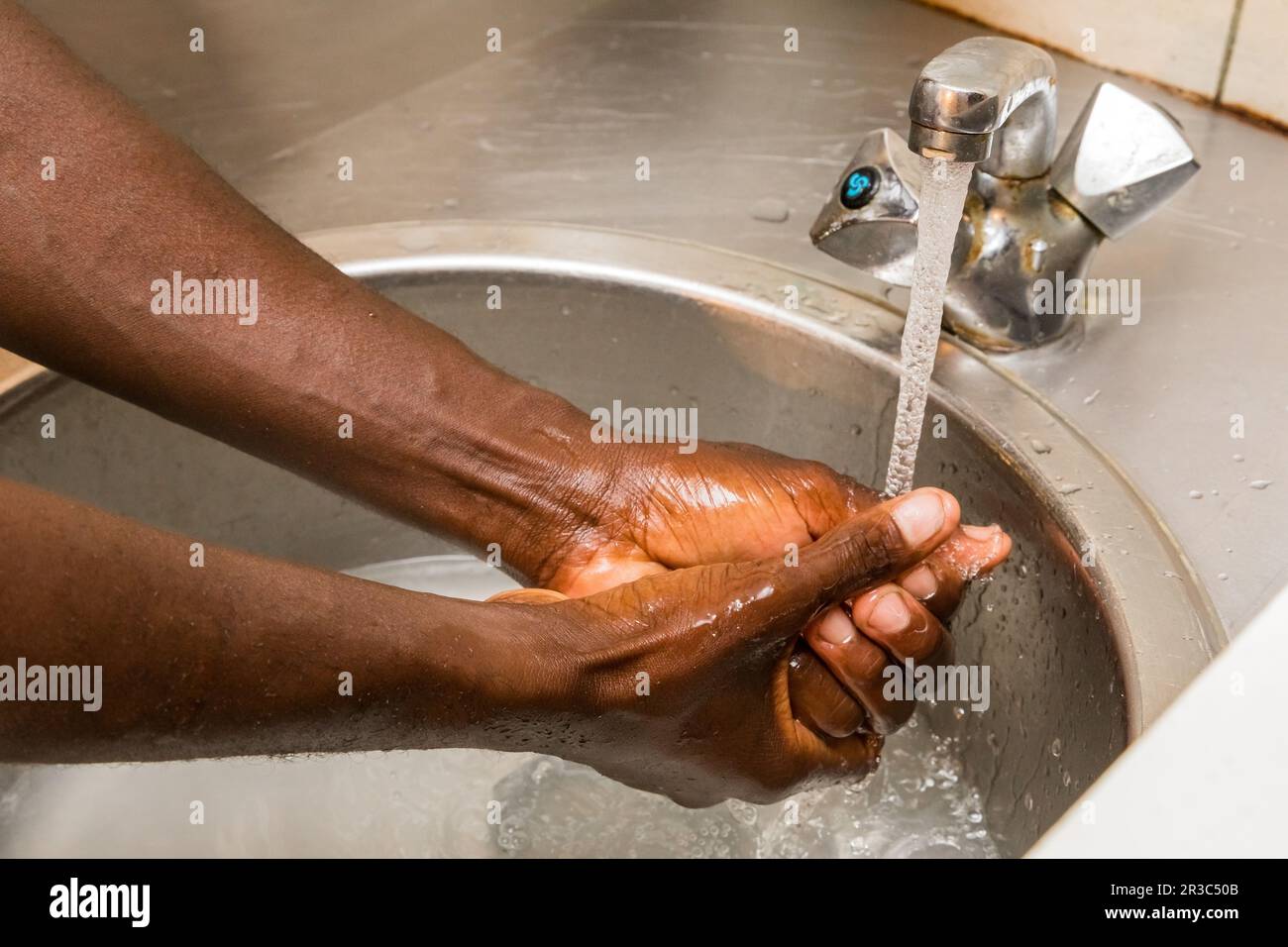 African person washing hands in basin to protect against spread of virus Stock Photo