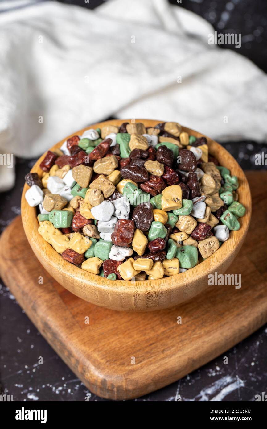 Colorful chocolate candy stones. Stone chocolate dragee in wooden bowl