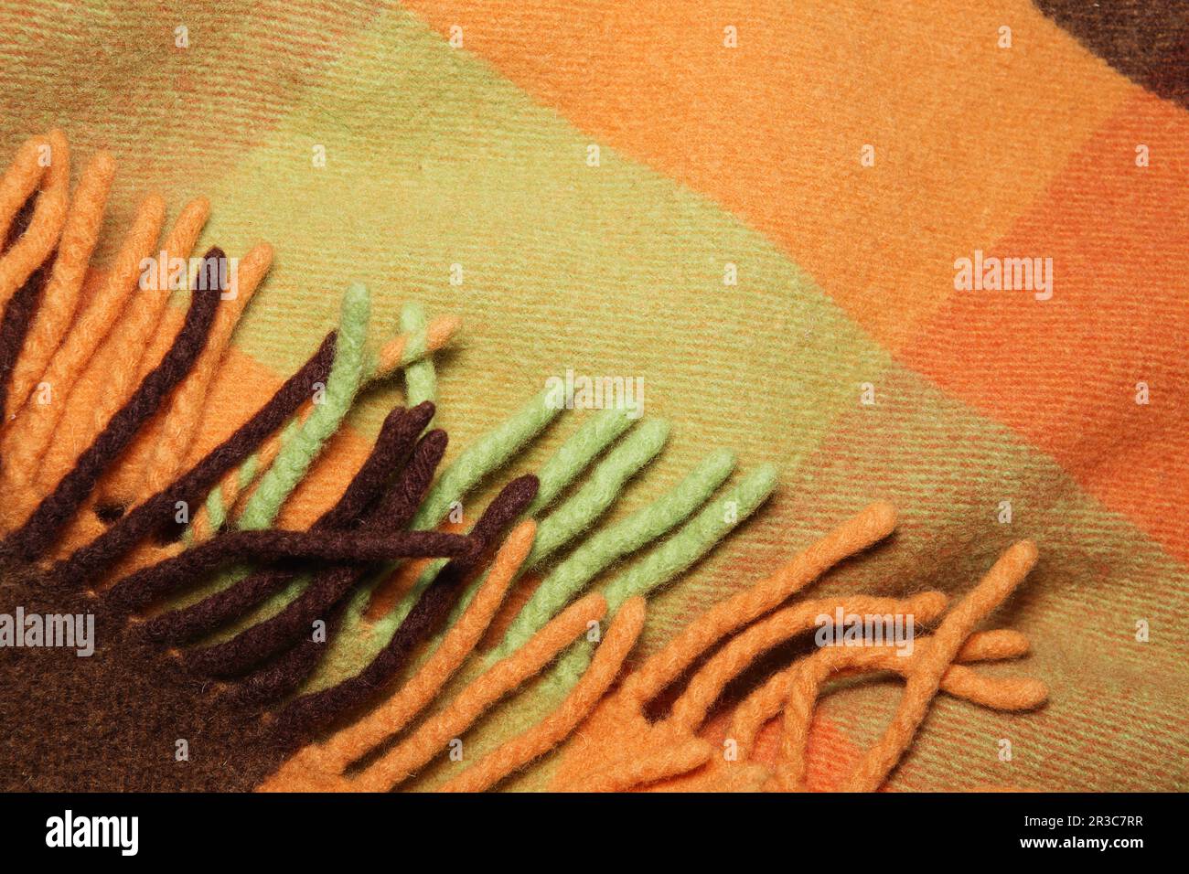 Soft and warm folded alpaca wool blanket with fringe. Green and orange wool plaid texture macro shot Stock Photo