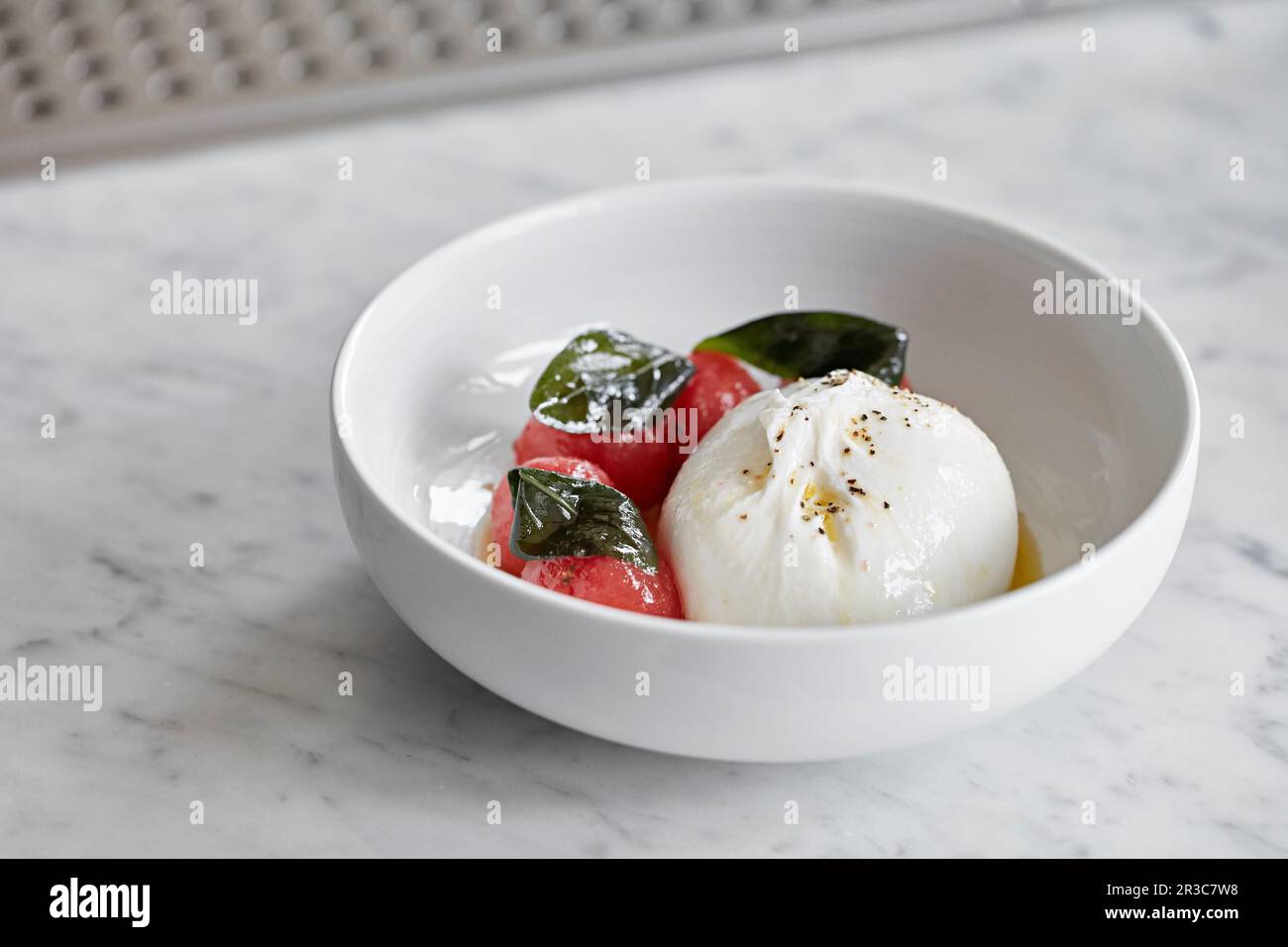 Burrata served with balls of watermelon and drizzled with olive oil Stock Photo