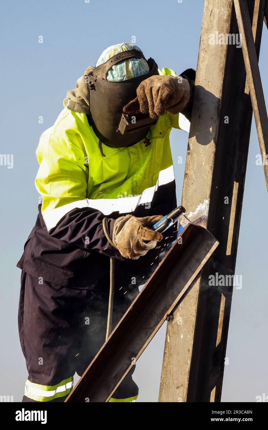 Man welding metal on a construction site, Tradesman working with welding torch Stock Photo