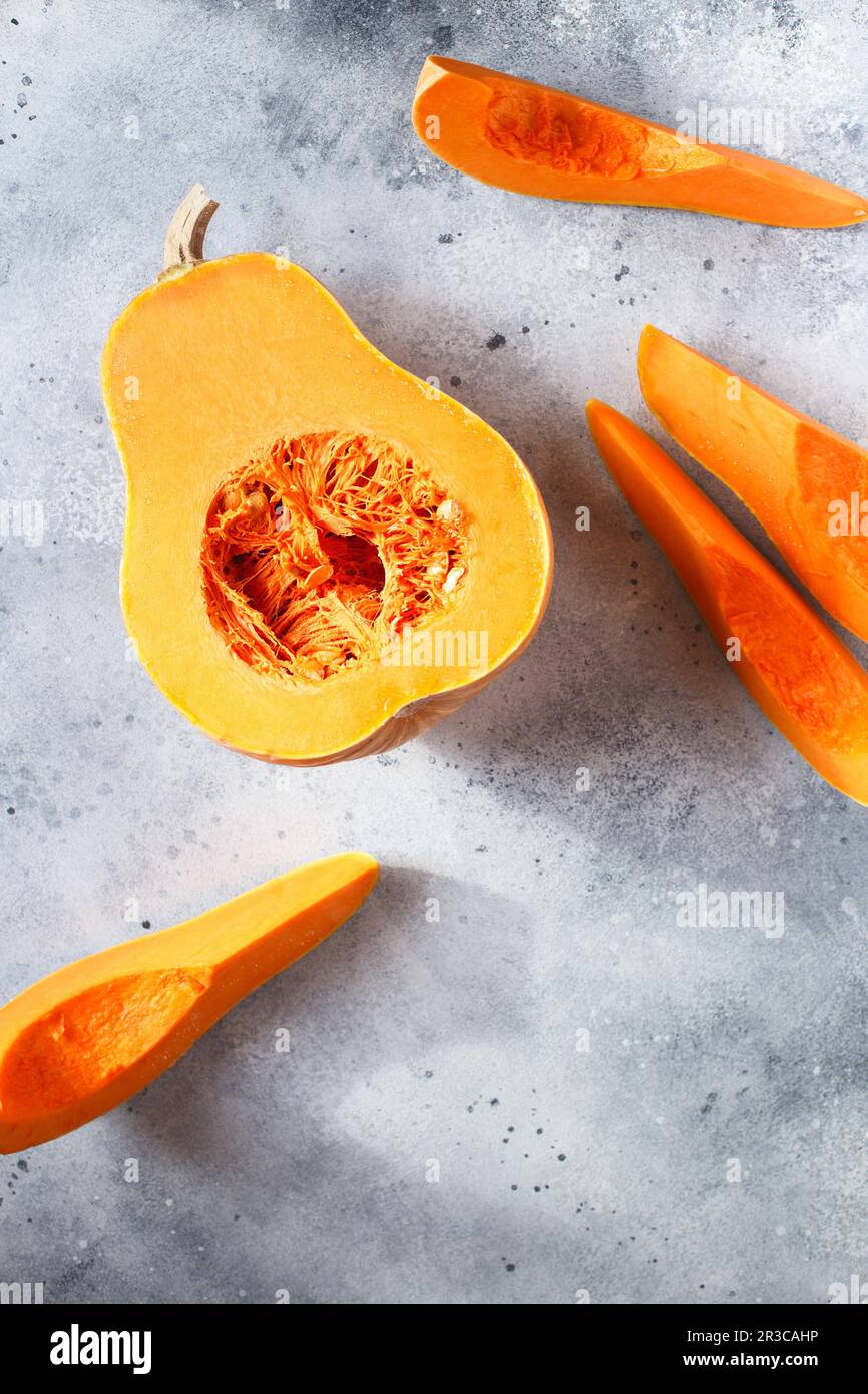 Fresh butternut squash on the grey background. Butternut Pumpkin. Halves of raw orange pumpkin. Cont Stock Photo