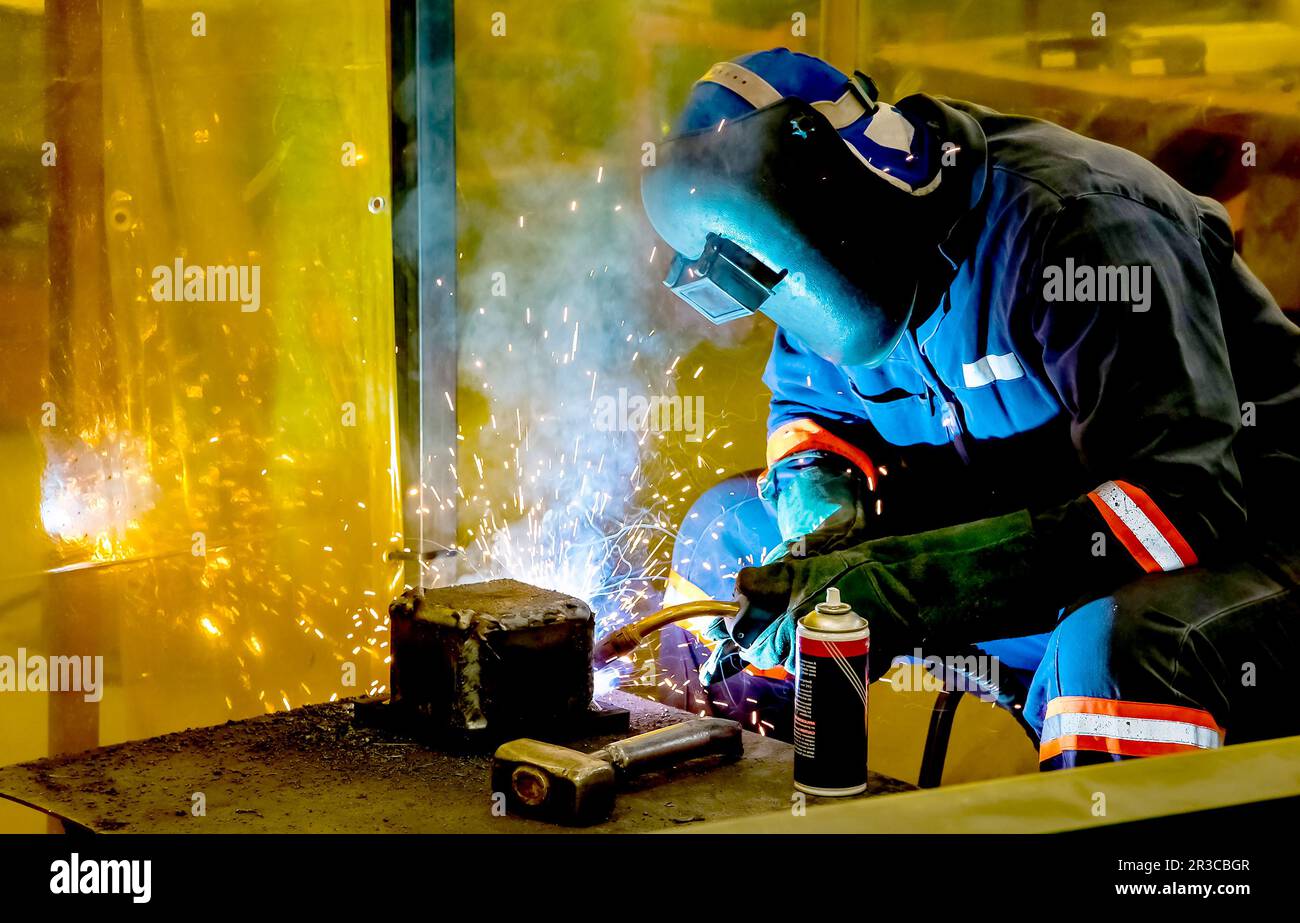 Man welding metal in a workshop, Tradesman working with welding torch Stock Photo