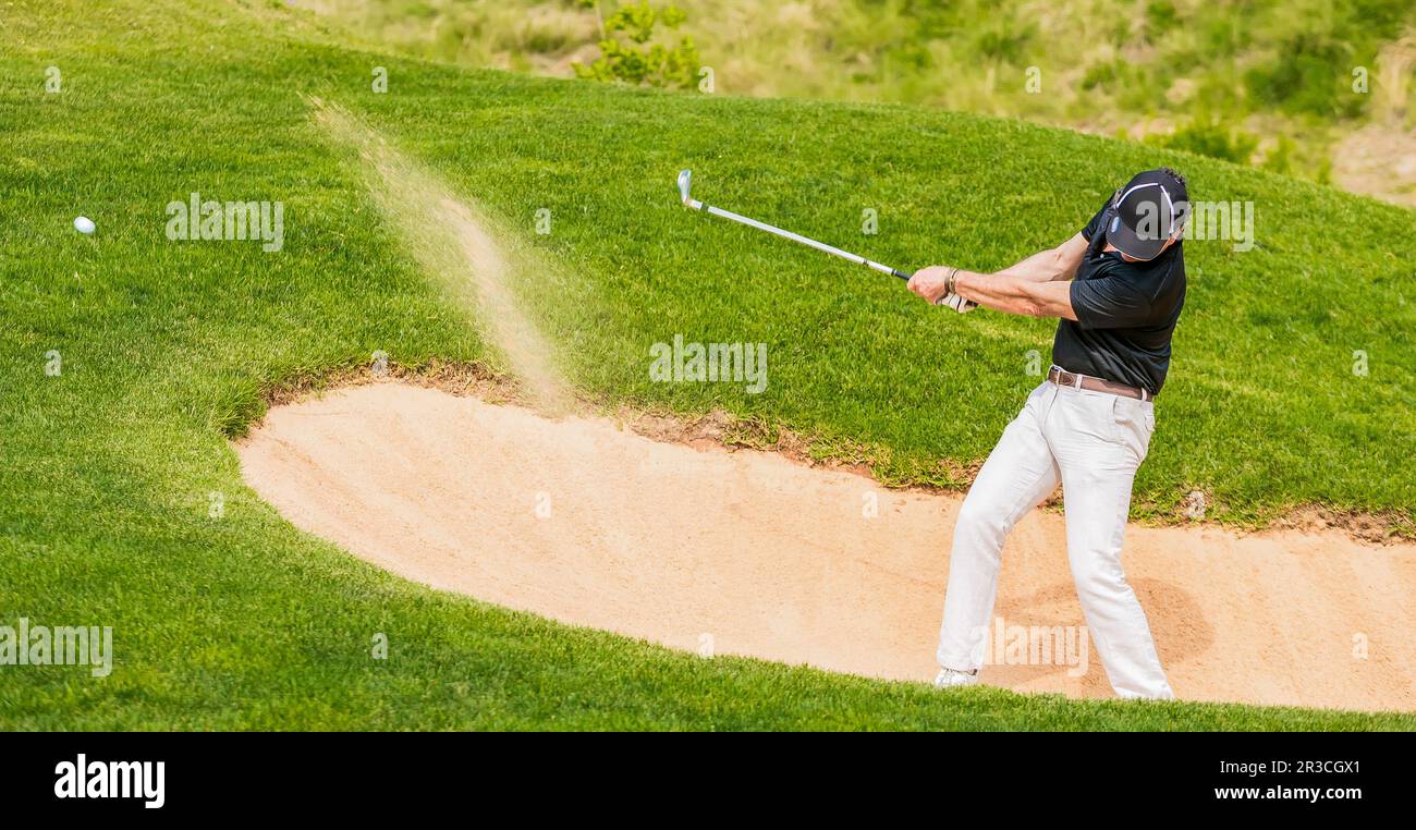 Man hitting golf ball out of a bunker Stock Photo