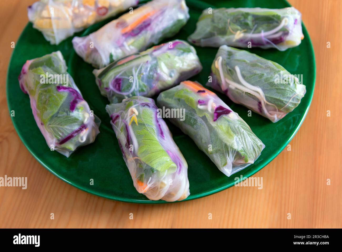 Fresh Spring Rolls on large green plate, view from above. Raw vegan dish, Vietnamese appetizer or main course, colourful vegetables wrapped in rice pa Stock Photo