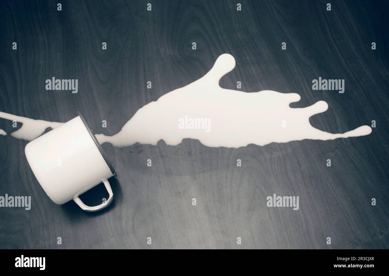 A jug of milk spilled on wooden floor Stock Photo
