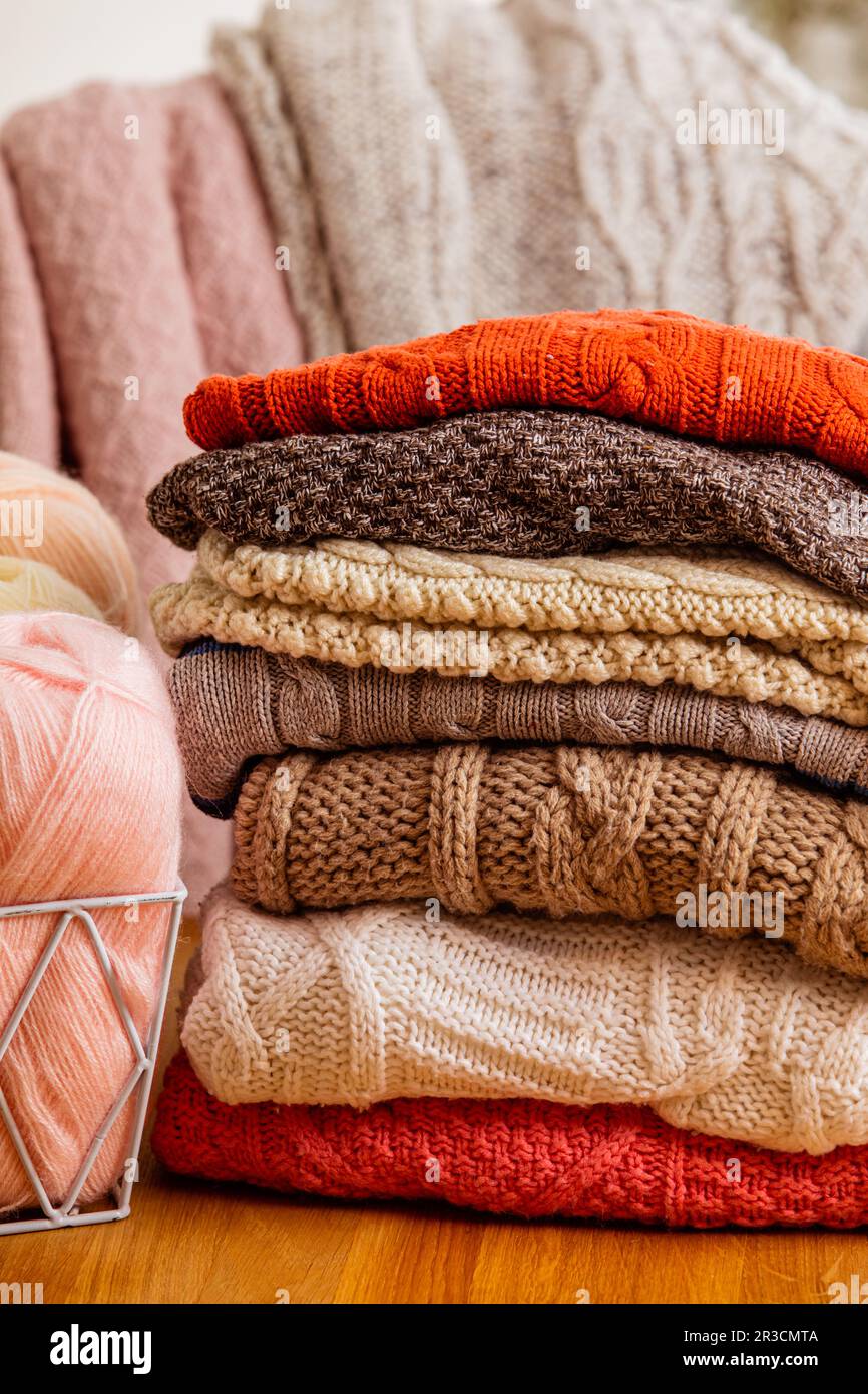 Pile of beige woolen clothes on a white background. Warm knitted sweaters and scarfs are folded in one heap. Stock Photo