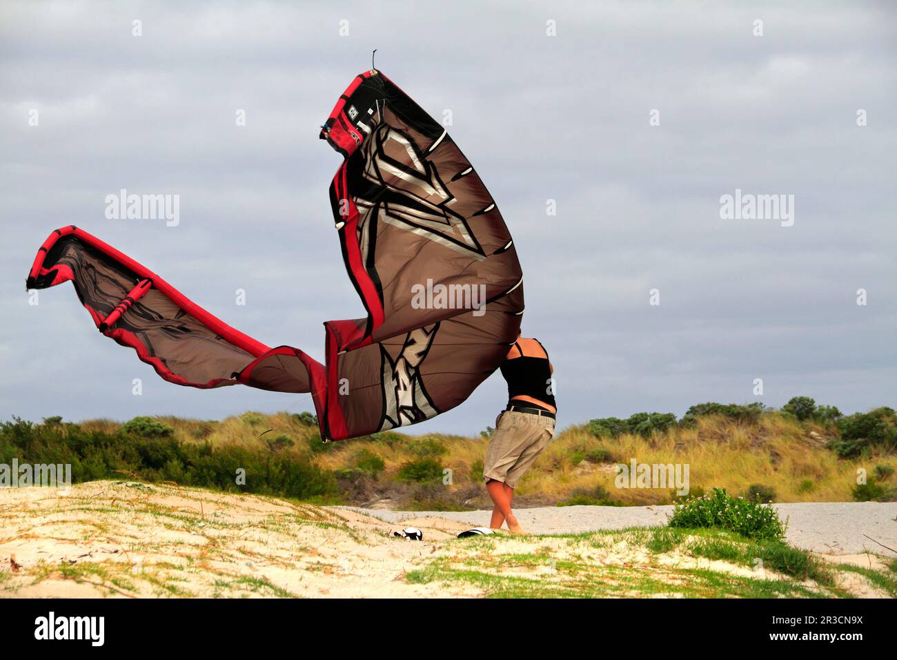 Young woman trying to control a board surf  kite in the wind on foreshore at,  Augusta,  Southwest Australia Stock Photo