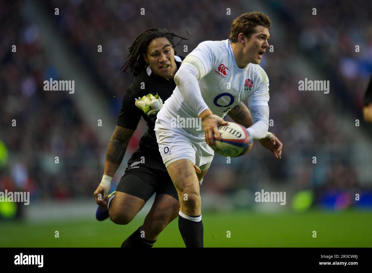 Alex Goode of England passes as he is hunted down by Ma'a Nonu of New Zealand during the QBE Autumn International match between England and New Zealan Stock Photo