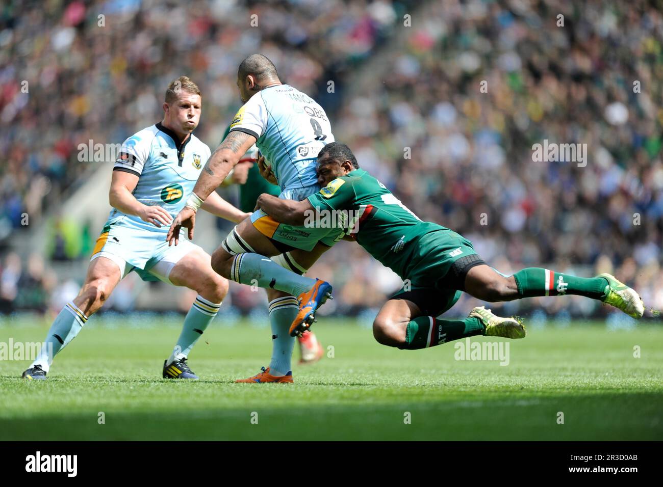 Samu Manoa of Northampton Saints is tackled by Vereniki Goneva of Leicester Tigers as Dylan Hartley of Northampton Saints looks on during the Aviva Pr Stock Photo